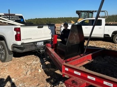 White Warrior Waste truck and red trailer on a gravel job site