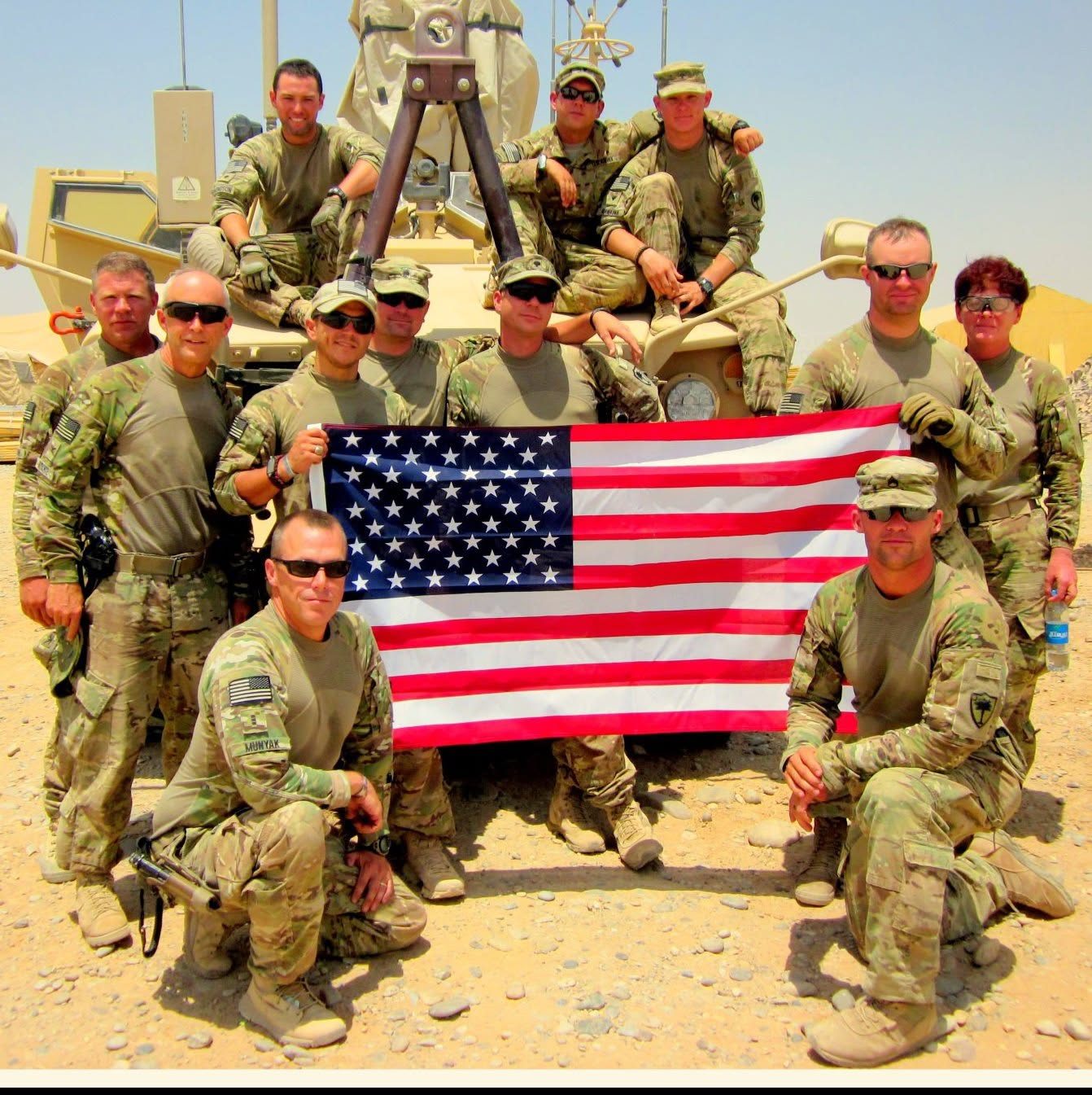 U.S. Army soldiers with an American flag beside an armored vehicle
